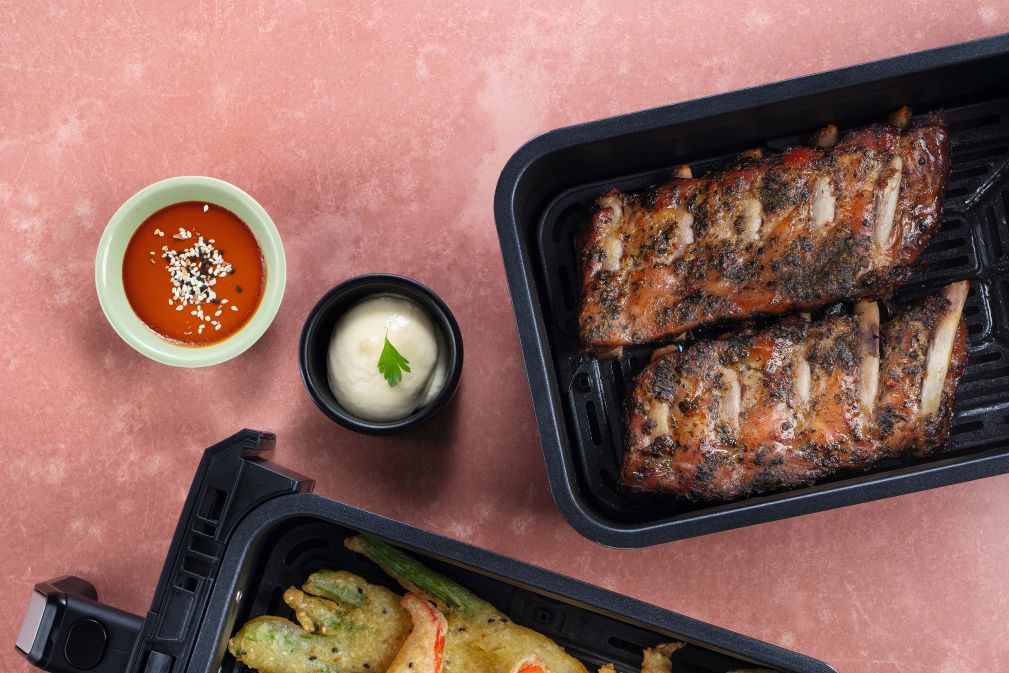 Spareribs im Airfryer neben knusprigem Gemüse im Tempurateig im Airfryer und zwei Dips