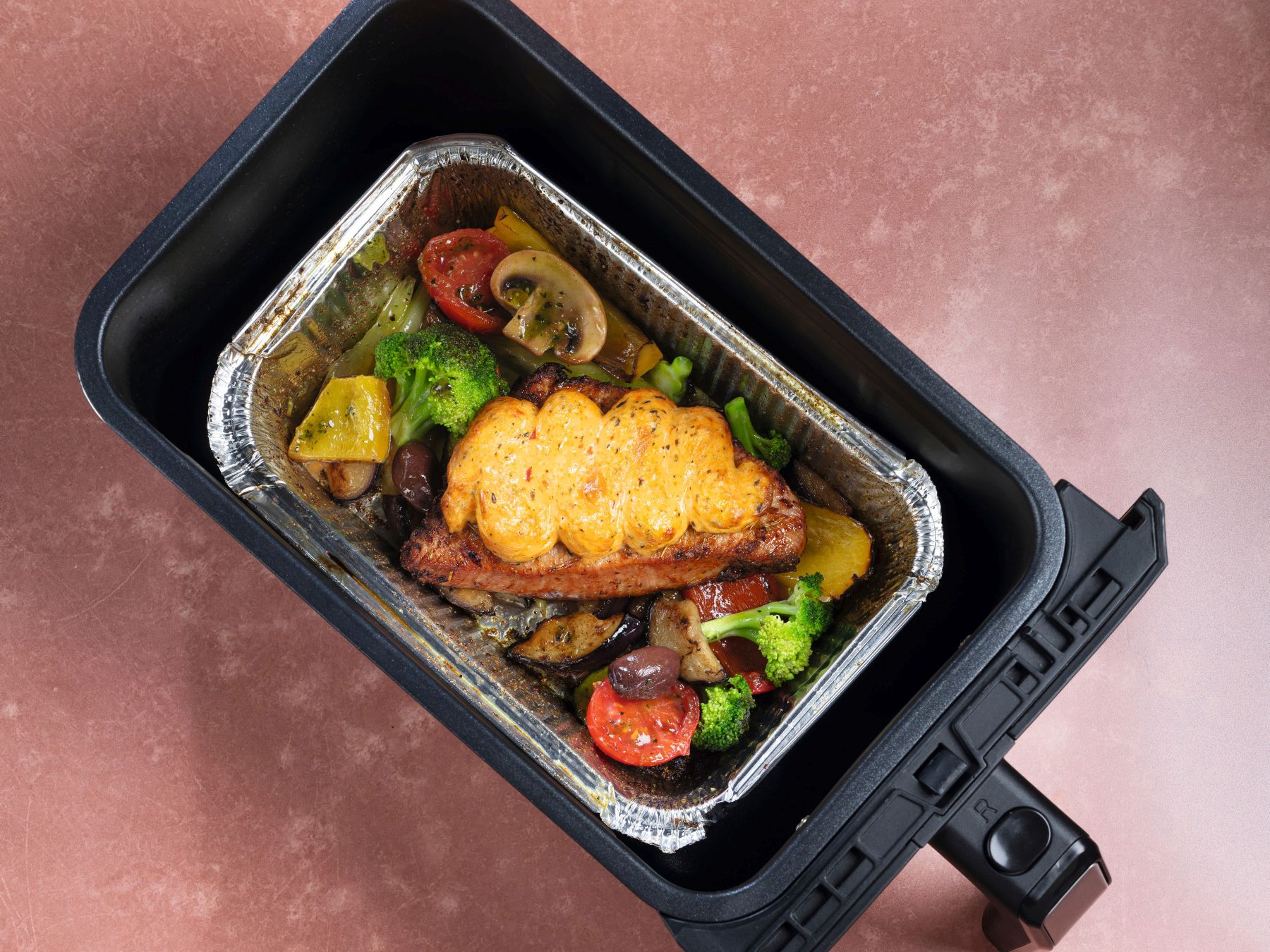 Überbackenes mediterranes Putensteak mit Gemüse im Airfryer und angerichtete Portion auf einem Teller