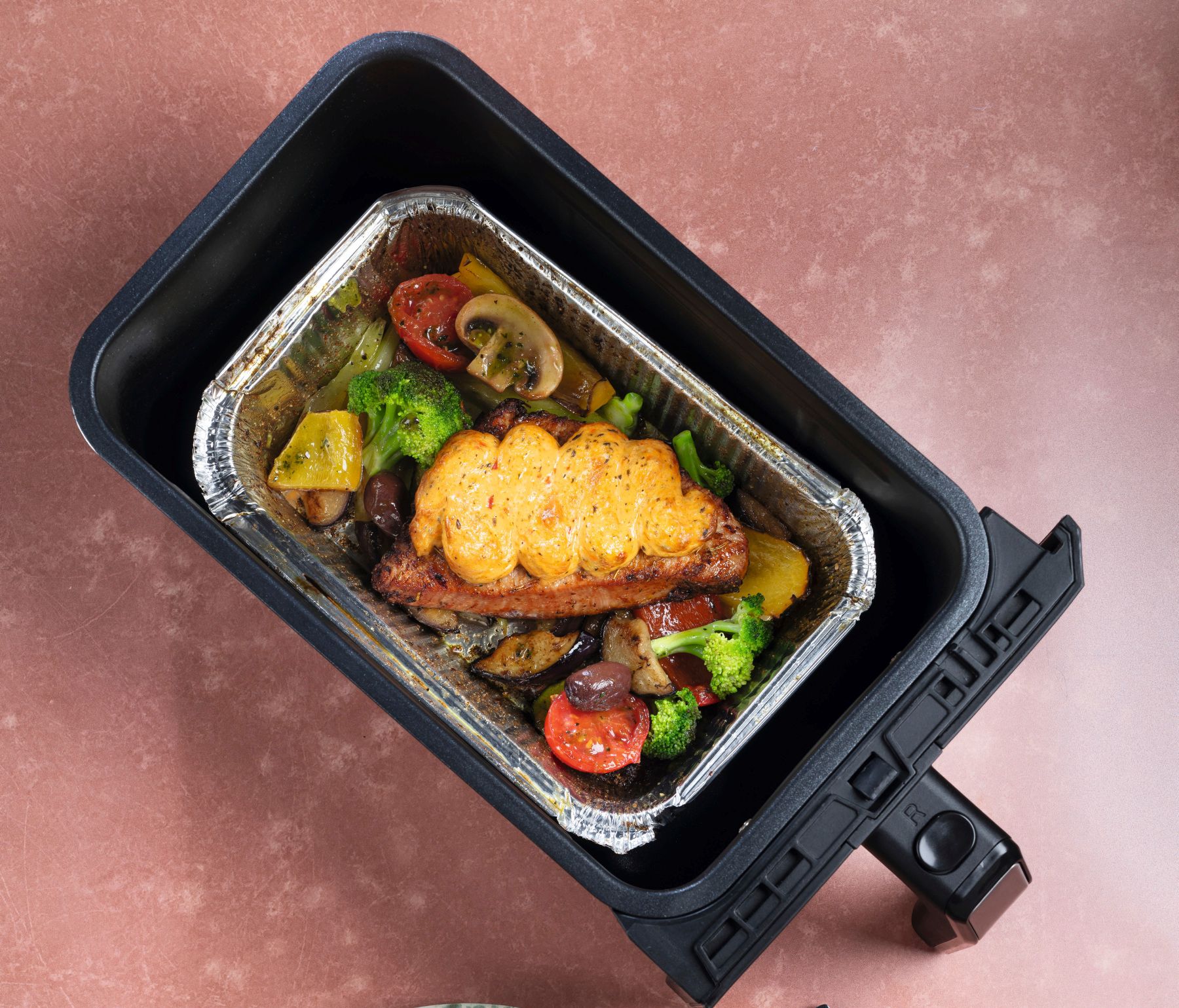 Überbackenes mediterranes Putensteak mit Gemüse im Airfryer und angerichtete Portion auf einem Teller