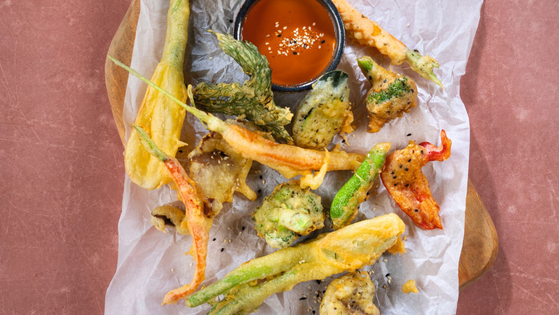 Knuspriges Gemüse im Tempurateig mit roter Sauce, Zitrone und frischen Kräutern auf Backpapier
