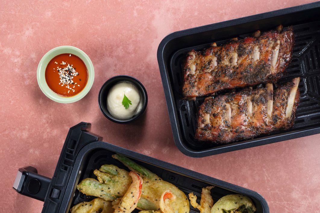 Spareribs im Airfryer neben knusprigem Gemüse im Tempurateig im Airfryer und zwei Dips