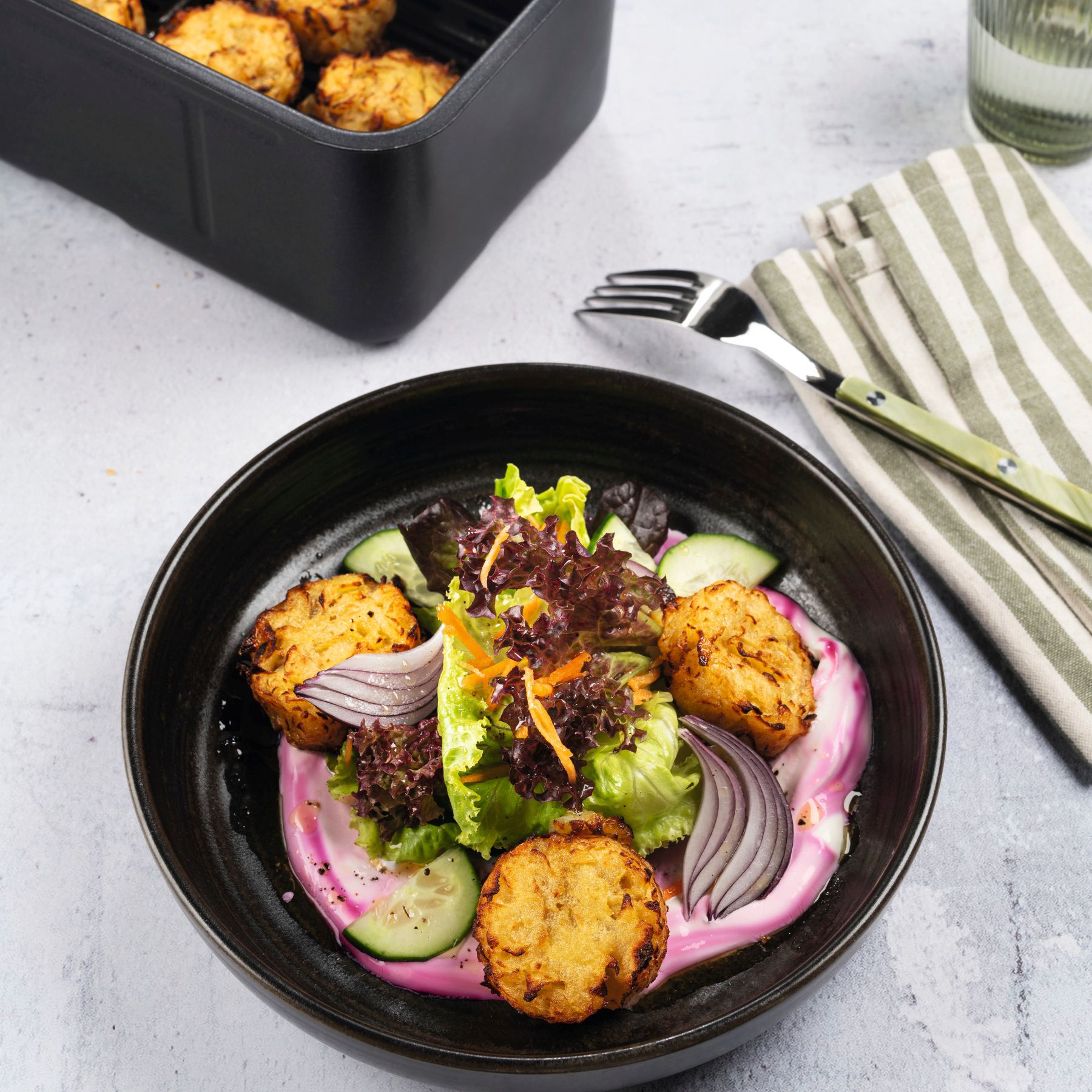 Knusprige Rösti-Taler im Airfryer und auf einem Salat mit Karotten und roten Zwiebeln