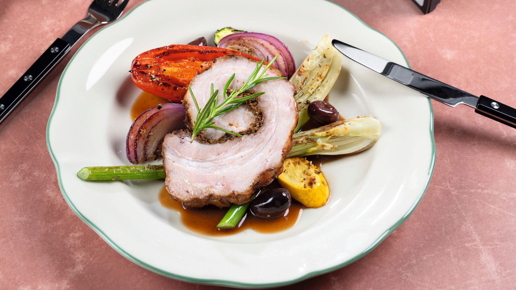 Aufgeschnittener Schweinerollbraten mit Gemüse, daneben der geöffnete Airfryer